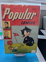Front cover of Popular Comics #133 in bag and board