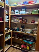 Wide view of pantry shelves showing jars, bowls, canisters, bakeware, plastic plates