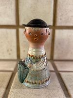Front view of signed Ilona Kiss Rooz ceramic woman figurine showing colour, form and basket