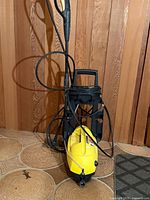 Front view of Karcher yellow pressure washer on black trolley with hose and gun
