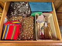 Drawer containing cloth napkins in various prints and colours, utensils and tray