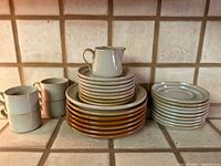 Overall view showing stacks of dinner plates, smaller plates, mugs and pitcher
