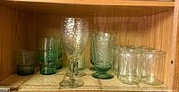 Cabinet shelf with green tumblers, hammered goblets and clear juice glasses