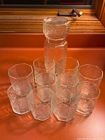 Pitcher standing behind eight tumblers showing octagonal form and chevron texture