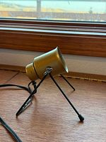 Side view of brass-tone spotlight on black tripod stand