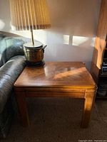 Full view of square oak side table positioned between sofa and shelf