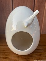 Front view showing egg shape, opening, and bird figurine
