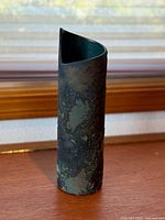 Front view of cylindrical ceramic vase with scroll rim and mottled raku glaze
