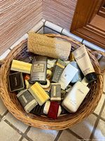 Top view of wicker basket showing multiple boxed soaps, lotion bottle, lotion tube, and loofah sponge