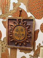Front view of square stoneware plaque showing entire sun face design and hanging loop