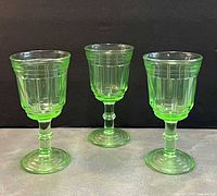 Front view of three green vaseline wine glasses