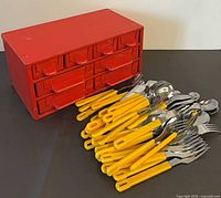 Flatware spread in front of red organizer cabinet