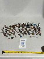 group shot of all 54 painted metal miniatures with tape for scale