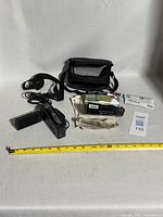 Lot overview showing camcorder, case, cable, manuals and measuring tape