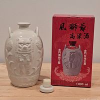 Front view of ceramic decanter and box, cap removed