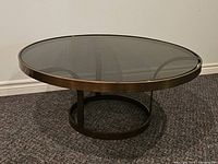 Side view of round coffee table showing smoked glass top and metal frame
