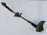 Full view of Toro corded electric trimmer lying flat, showing shaft, handle, debris guard and cutting head