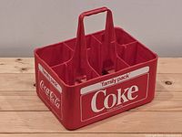 Oblique view showing red plastic six-slot Coca-Cola carrier