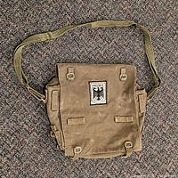 Front view of olive canvas satchel with eagle patch and shoulder strap