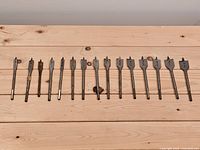 All 14 spade drill bits laid out to show full lengths and paddle heads