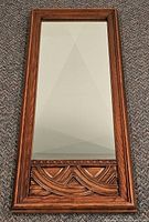 Front view of rectangular oak-framed mirror showing carved lower panel and mirror glass