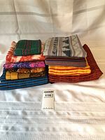 Stack of nine folded textiles in various colours and patterns