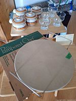 Lot overview showing Pampered Chef pizza stone, rack, box, four ceramic crocks, four glass dessert cups