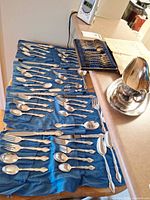 Overall view of flatware laid out in blue roll, boxed set, gravy boat