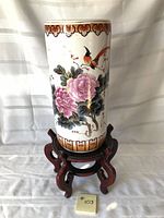 Full view of porcelain vase on wooden stand showing floral and bird motif