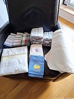 Grouped view of tablecloths and assorted dish towels on chair