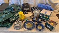 Entire lot displaying air mattress, air pump, lantern, stove, enamelware dining set, kettle, toaster, tarp, floor cover, salt & pepper shaker, flashlight
