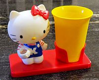 Front view of Hello Kitty toothbrush holder with yellow cup on red base