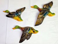 Front view of all three gloss-painted flying ducks