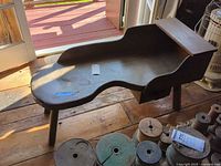 Top view of wooden cobbler's bench showing curved surface and legs
