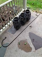 Three black metal lanterns and long shepherd’s hook laid on porch