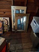 Both mirrors lean against wall; white wood frame mirror in back, pressed tin ornate frame mirror in front