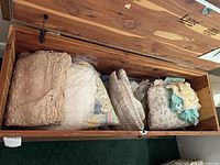Overview of cedar chest interior showing crochet afghans, quilted and knit baby items
