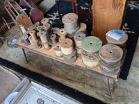 Bench holding numerous wooden spools in varying sizes and colors