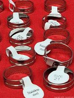 Close-up of several rings showing polished finish and twin grooves, size tabs visible