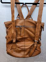 Front view of brown leather backpack showing exterior zip pocket and straps