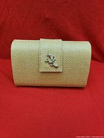 Front view of woven paper straw clutch with coral clasp