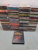 Front view of large stack of CDs with one DVD case on table