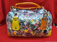 Front view of Nahui Ollin woven handbag highlighting multicolor pattern, yellow tabs, orange handle