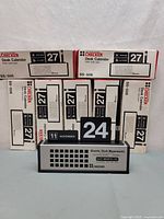 Front view showing open sample calendar with date cards and pen, boxed units stacked behind