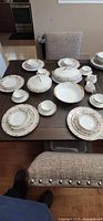 Full set laid out on dining table showing plates, bowls, cups, covered dishes