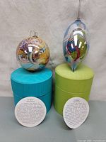 Both ornaments on boxes with cards displayed