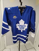 Front view of blue Toronto Maple Leafs CCM jersey on hanger