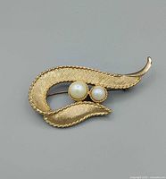 Front view of gold-tone swirl brooch with faux pearls