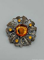 Front of ornate thistle brooch showing amber stones