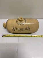Overall top view of stoneware foot warmer with measuring tape